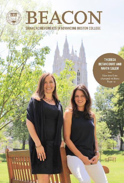 Two women are smiling, standing on a sunny grassy area with trees and a large building in the background. They are featured on the cover of Beacon magazine, with a headline about their achievements.