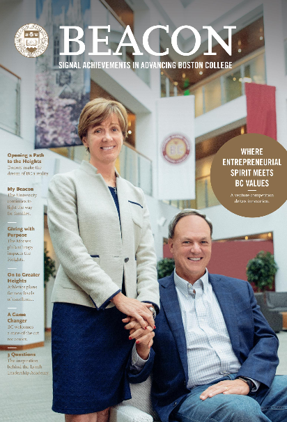 A woman in a light blazer stands next to a seated man in a blue shirt inside a modern building. "Beacon" magazine cover with text about Boston College values and achievements. Bright atrium with plants and banners in the background.